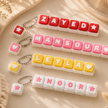 Personalized bold name keychain with red, pink, and yellow letter blocks and heart charms.
