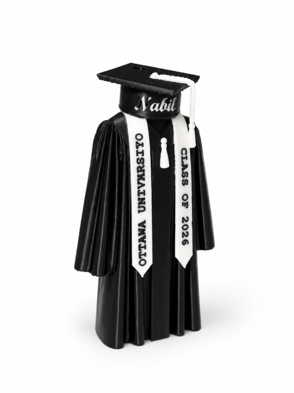 Personalized graduation figurine in graduation gown and cap, university sash detail.