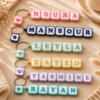 Row of clicker name keychains in different colors spelling custom names with heart and star charms - Forjolie.dxb