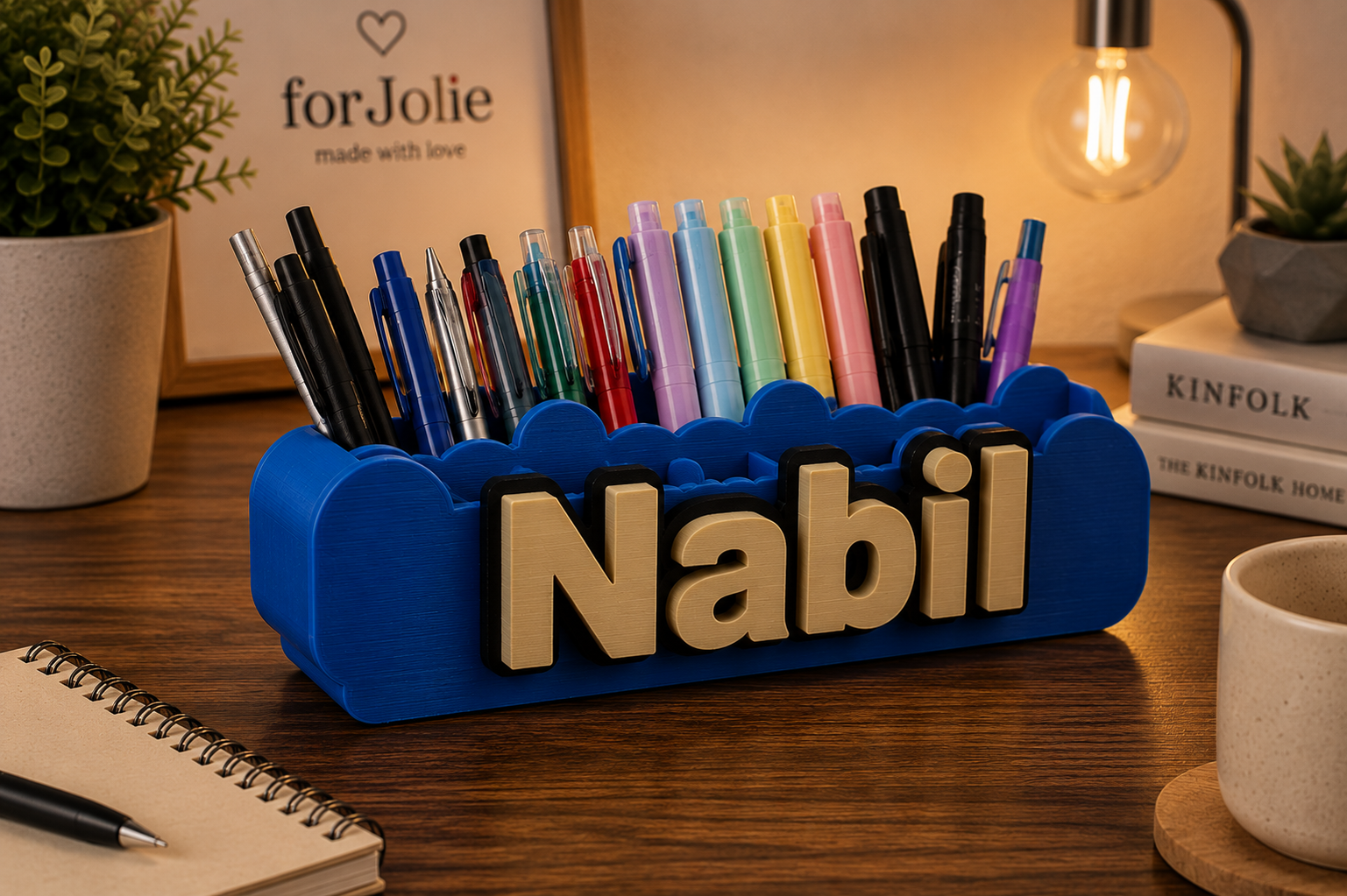 Personalized name pen holder with "Nabil" in gold lettering, assorted colorful pens and stationery.